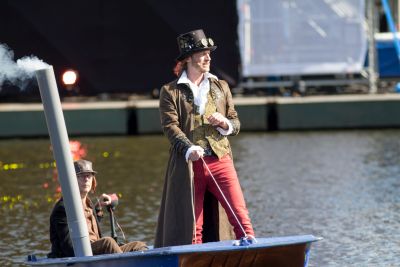 Man in steampunk kleding staat op bootje