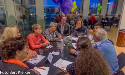 Verschillende mensen zitten met elkaar om tafel