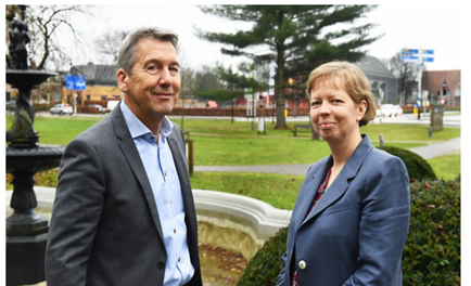 De ombudsman links en de plaatsvervangend ombudman rechts in een park met op de achtergrond een kruispunt van wegen. In het park een grote boom.  